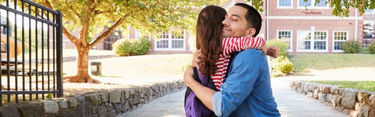 Daughter hugs her father in their driveway as she arrives home from her blended family summer visitation