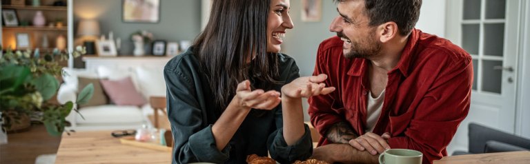 happily married couple sitting at a breakfast bar having coffee in their home while having some fun conversation